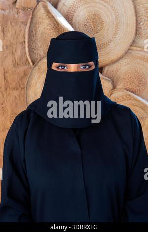 Primo piano di una bella e misteriosa signora in abbigliamento tradizionale (abaya, tarhah e niqab) ad Alula, Arabia Saudita Foto Stock