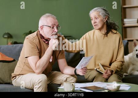 Senior coppia caucasica che discute documenti finanziari mentre si siede insieme Foto Stock