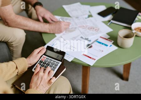 Donna caucasica anziana che utilizza Calcolatrice durante la revisione dei documenti finanziari Foto Stock