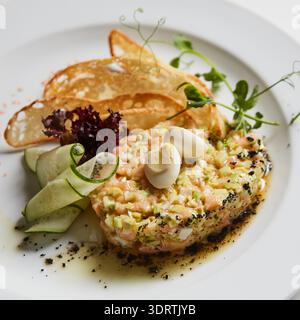 Metti in mostra l'autentica specificità regionale con questa vivace tartare di salmone, caratterizzata da texture locali, verdure fresche e patatine artigianali per un look fedele Foto Stock