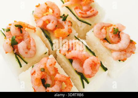 Collezione di pezzi di sushi con gamberi e condimenti su un piatto bianco Foto Stock