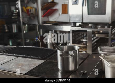 Collezione di utensili e attrezzature da cucina in un ambiente di lavoro con postazioni di cottura Foto Stock