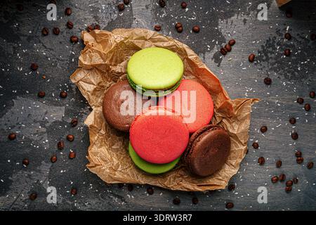 Macaron colorati su carta con chicchi di caffè Foto Stock