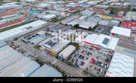 Veduta aerea di un'estesa area industriale con file di magazzini, fabbriche e auto parcheggiate sotto un cielo morbido, Cáceres, Estremadura, Spagna. Foto Stock