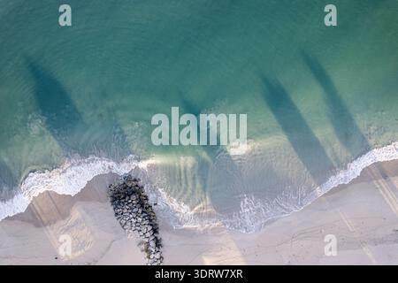 Vista aerea delle acque turchesi che incontrano la spiaggia sabbiosa con ombre aspre e onde spumose, Mandurah, Australia Occidentale, Australia. Foto Stock