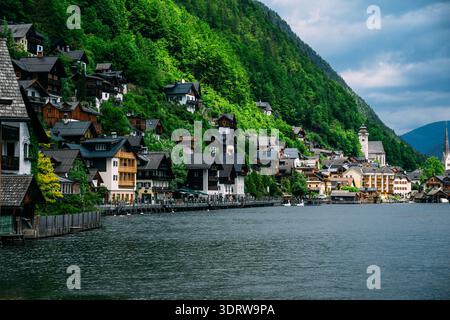Pittoresco villaggio austriaco accoccolato su una ripida e verde montagna che si affaccia su un tranquillo lago Foto Stock