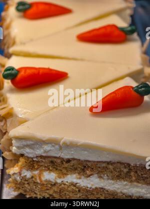 Foto della sezione di torta alla carota con glassa al formaggio e decorazione della carota al marzapane primo piano sfondo verticale. Foto Stock