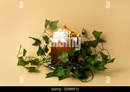 Torta di Pasqua adornata con foglie verdi fresche su sfondo di pesca chiaro, elegante presentazione delle vacanze primaverili Foto Stock