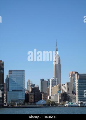 Una vista panoramica dello skyline di New York vista dall'altra parte dell'acqua, con in primo piano l'Empire State Building. Foto Stock