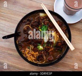 Zuppa di manzo con spaghetti e verdure su fondo di legno Foto Stock