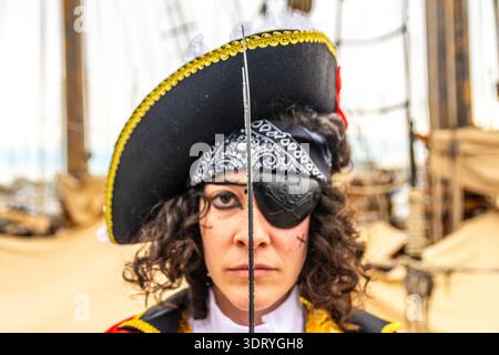Donna vestita con un dettagliato costume da pirata, indossa un occhiello e un cappello, che si posa con una spada in verticale alla vigilia del carnevale Foto Stock