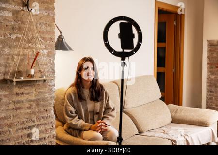 Donna che crea contenuti coinvolgenti con smartphone e luce anulare Foto Stock