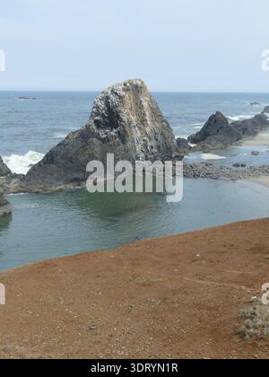 , Seal Rock, vicino a Newport, Oregon Seal Rock che sorge nell'Oceano Pacifico vicino a Newport, Oregon, con acque calme che riflettono il cielo e una spiaggia sabbiosa Foto Stock
