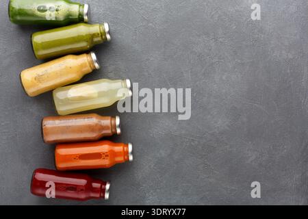 Varie bottiglie di succo allineate su una superficie grigia che mostra colori e sapori diversi Foto Stock