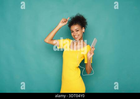 Happy Young Woman balla mentre ascolti musica con il suo smartphone in un ambiente luminoso Foto Stock