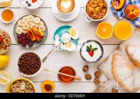 Collezione colazioni luminosa e colorata allestita su un tavolo di legno alla luce del mattino Foto Stock