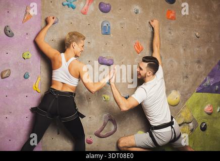 Gli arrampicatori si divertono e giocano su una luminosa parete interna per arrampicata Foto Stock