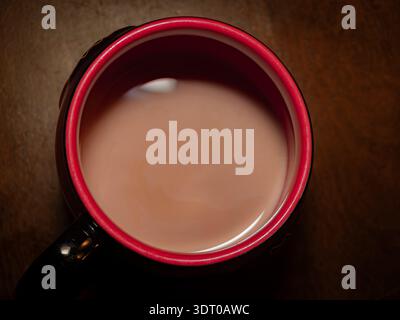Vista dall'alto verso il basso di una tazza di caffè con latte su un tavolo in legno, che cattura calore, comfort e relax Foto Stock