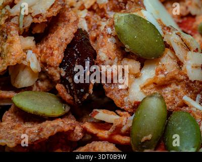 Macro primo piano di cereali misti per colazione con semi di zucca, noci e frutta secca, simbolo di una sana alimentazione e consistenza Foto Stock