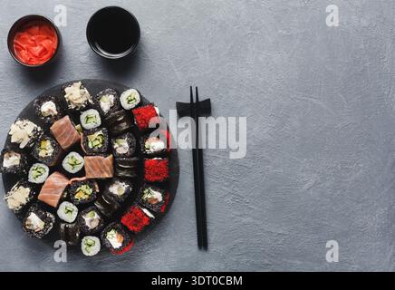 Piatto di sushi con vari panini e salse servito su un tavolo grigio Foto Stock
