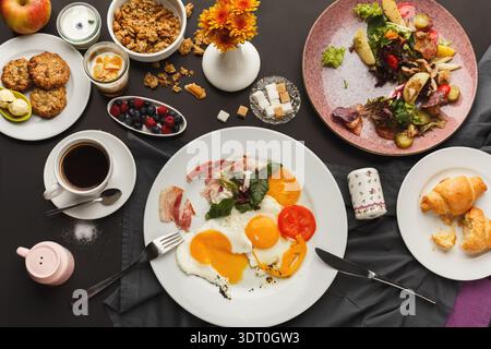 Selezione di cibi da colazione disposti su un tavolo con vari piatti e bevande in vista Foto Stock