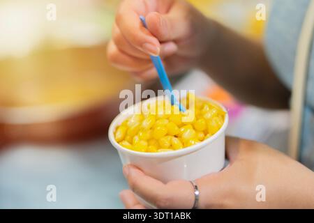 Mais cotto con burro in un bicchiere di carta bianca su una donna che tiene le mani. Cibo delizioso della Thailandia, molto delizioso. I thailandesi sono i migliori. Foto Stock