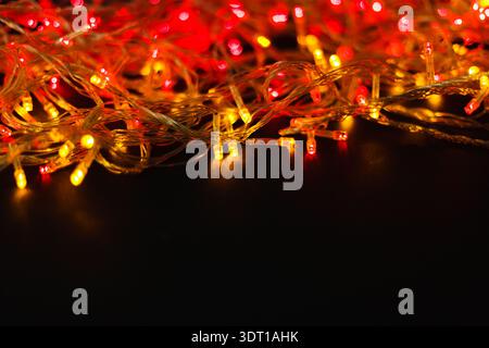 Le luci colorate creano un vivace collage di tonalità rosso e giallo su una superficie scura Foto Stock