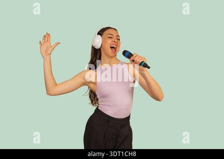 Giovane donna che canta appassionatamente mentre ascolta musica con le cuffie Foto Stock