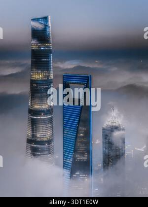 Veduta aerea dei grattacieli che piergono attraverso la fitta nebbia, la loro architettura moderna in contrasto con la nebbia eterea, Shanghai, Cina. Foto Stock