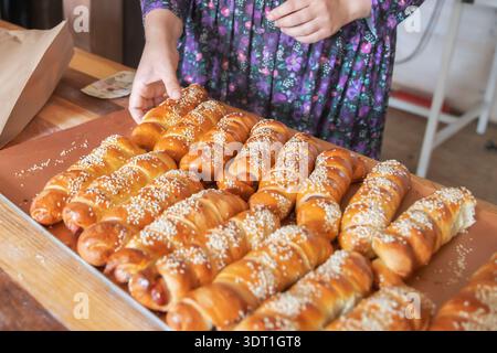 Involtini di salsiccia avvolti nell'impasto con semi di sesamo su vassoio da forno Foto Stock