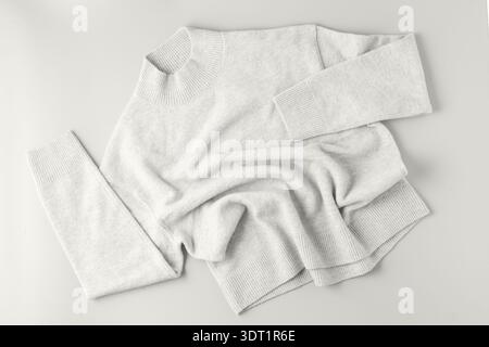 Morbido pullover di lana merino bianca melange e cashmere su sfondo grigio chiaro. Abbigliamento in pura lana per l'autunno e l'inverno Foto Stock