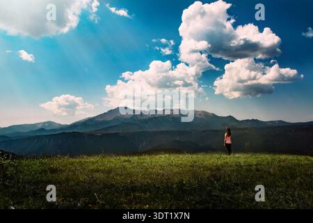 Donna in piedi sulla montagna che guarda in lontananza Foto Stock