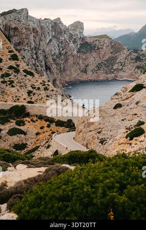 Strada tortuosa attraverso le scogliere sopra una baia, Cap de Formentor, Maiorca Foto Stock