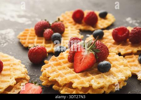 Waffle con varie bacche disposte su una superficie scura in stile collage Foto Stock