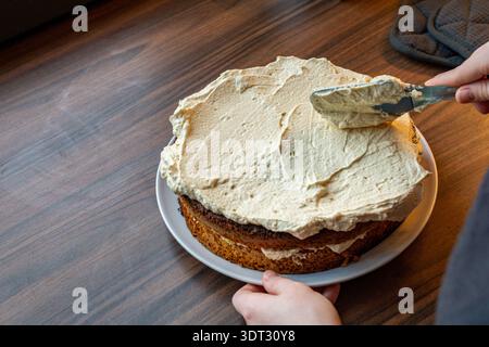 Una spatola che consente di ottenere una finitura liscia della glassa su una torta fatta in casa a due strati. Foto Stock
