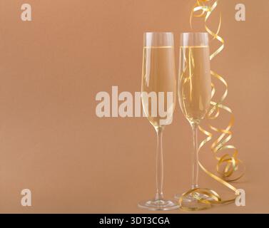 Collage di due flauti di champagne su sfondo marrone con nastro giallo per festeggiare Foto Stock