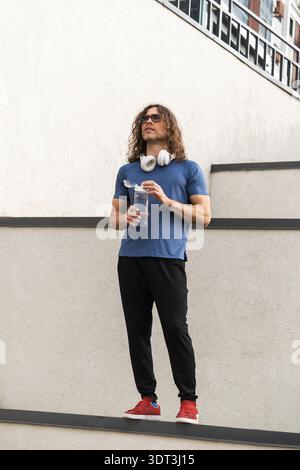 Uomo sportivo e sicuro in piedi sul bordo in un ambiente urbano Foto Stock