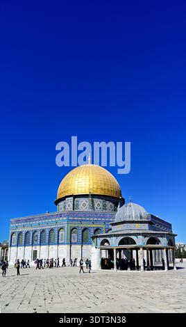 Le persone camminano intorno alla moschea della Cupola della roccia sul Monte del Tempio a Gerusalemme sotto un cielo azzurro chiaro durante le ore diurne. Foto Stock