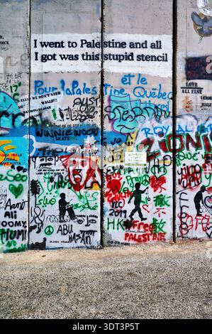 Le persone esprimono i loro pensieri sul muro di separazione a Betlemme, con graffiti e stencil che coprono la superficie in cemento. Foto Stock