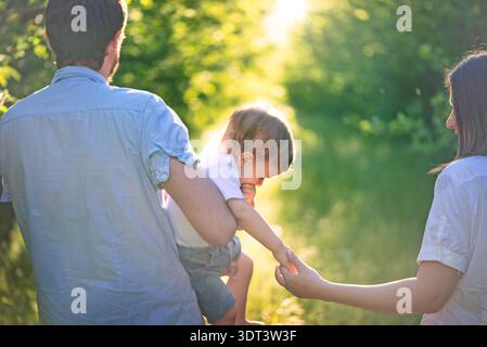 La famiglia cammina insieme su un sentiero soleggiato nella foresta in estate Foto Stock
