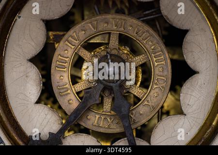 Macro primo piano di un antico meccanismo di orologio in ottone che mostra numeri romani e intricate lancette in metallo Foto Stock