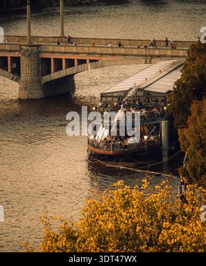 Scena serale sul fiume. Serena scena del crepuscolo con i visitatori sul lungomare sotto gli archi di pietra senza tempo Foto Stock