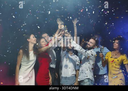 Festeggiamenti con gli amici durante una festa in un'atmosfera vivace con Confetti in the Air Foto Stock