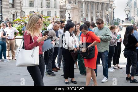 Giovane donna intelligente, che controlla il telefono, fuori dalla Banca d'Inghilterra. Foto Stock