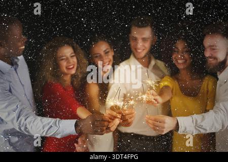 Gli amici festeggiano con gli Sparklers durante una festa notturna in un'atmosfera festosa Foto Stock