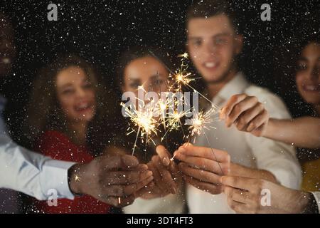 Gruppo di amici che festeggiano con Sparklers durante una serata gioiosa in un ambiente buio Foto Stock