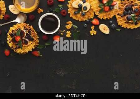 Collage di waffle con frutta e sciroppo su superficie scura Foto Stock