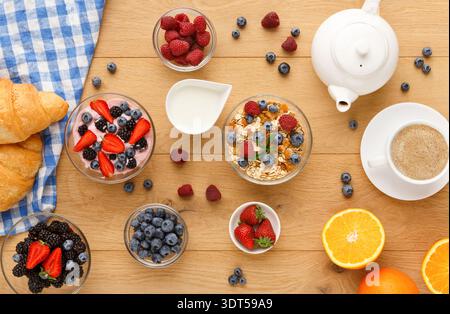 Colazione con vari tipi di frutta, yogurt e pasticcini su un tavolo di legno Foto Stock