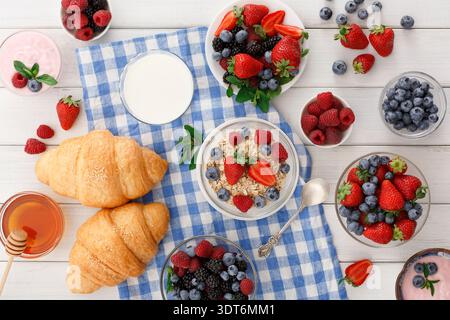 Il tavolo della colazione include frutta, yogurt, croissant e bevande in un ambiente da cucina Foto Stock