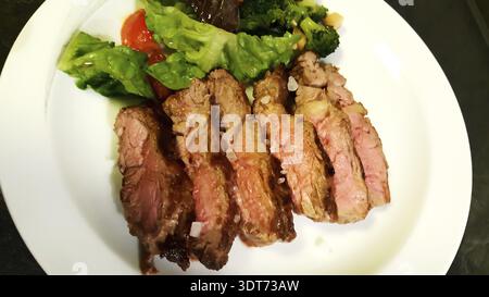 Carne grigliata a fette con contorno vegetale servita su un piatto Foto Stock